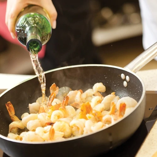 Chef cocinando con vino blanco